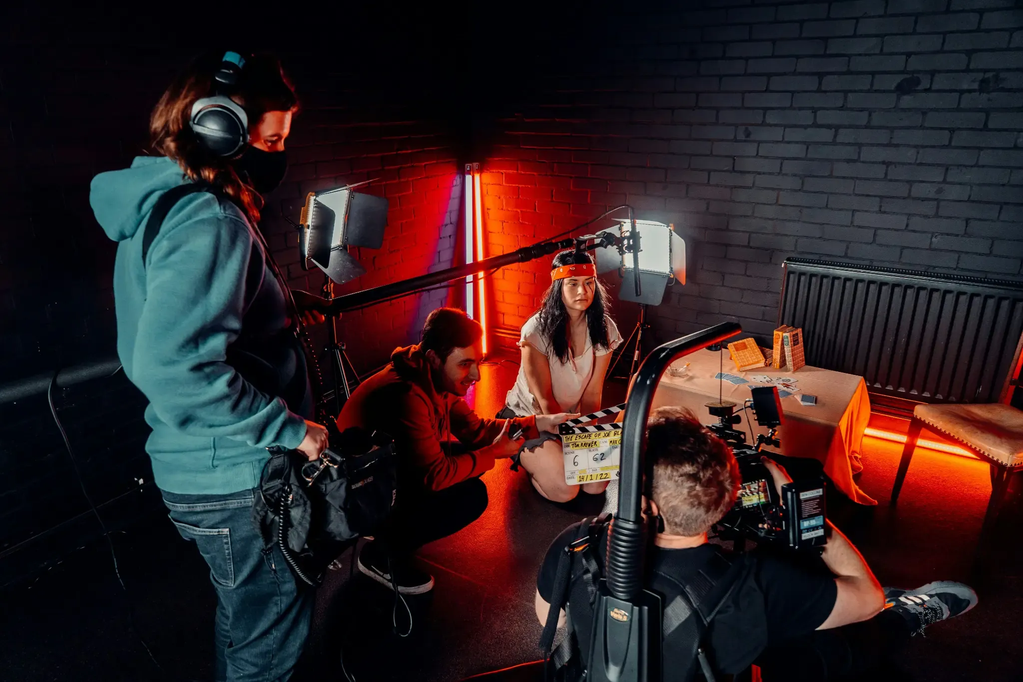 Film crew recording an actor on a set with red neon lighting.
